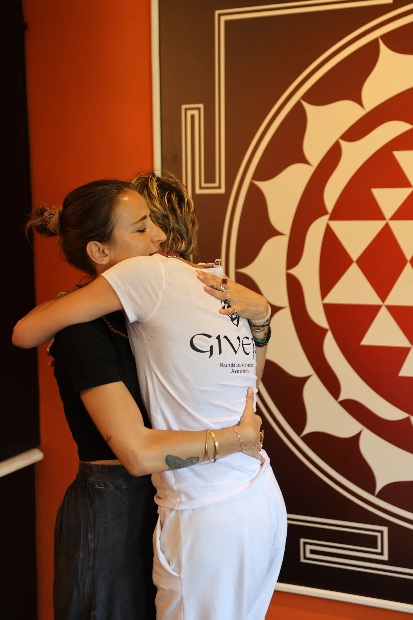 Two participants embracing before a Sri Yantra during the GIVER® training in Italy