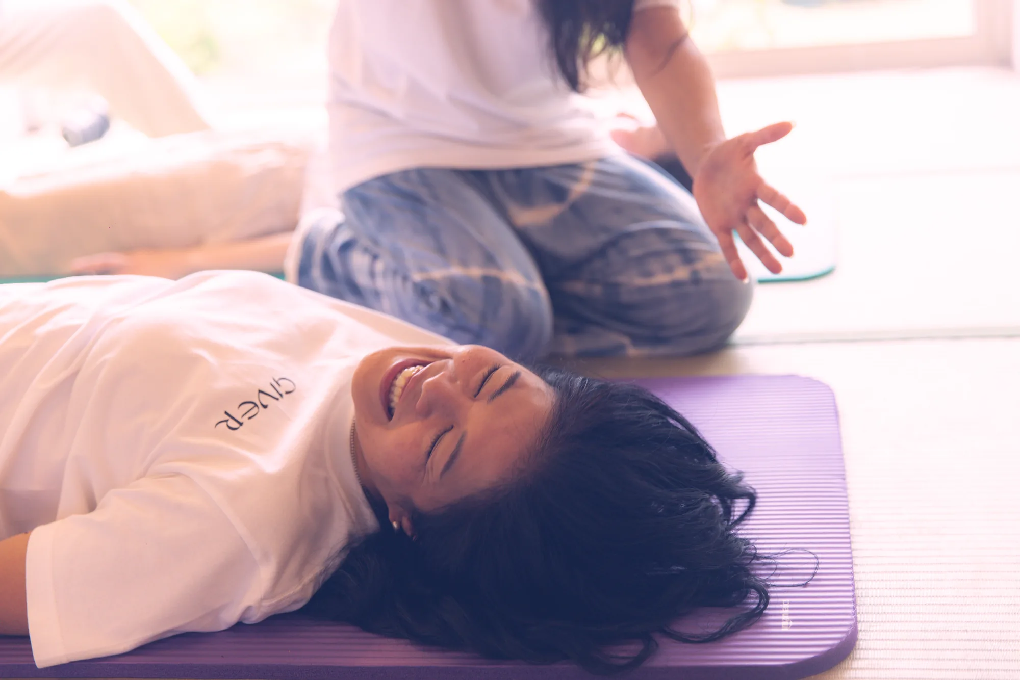 Woman laughing in emotional release while a facilitator holds space after a GIVER® Kundalini Activation Astral Work session