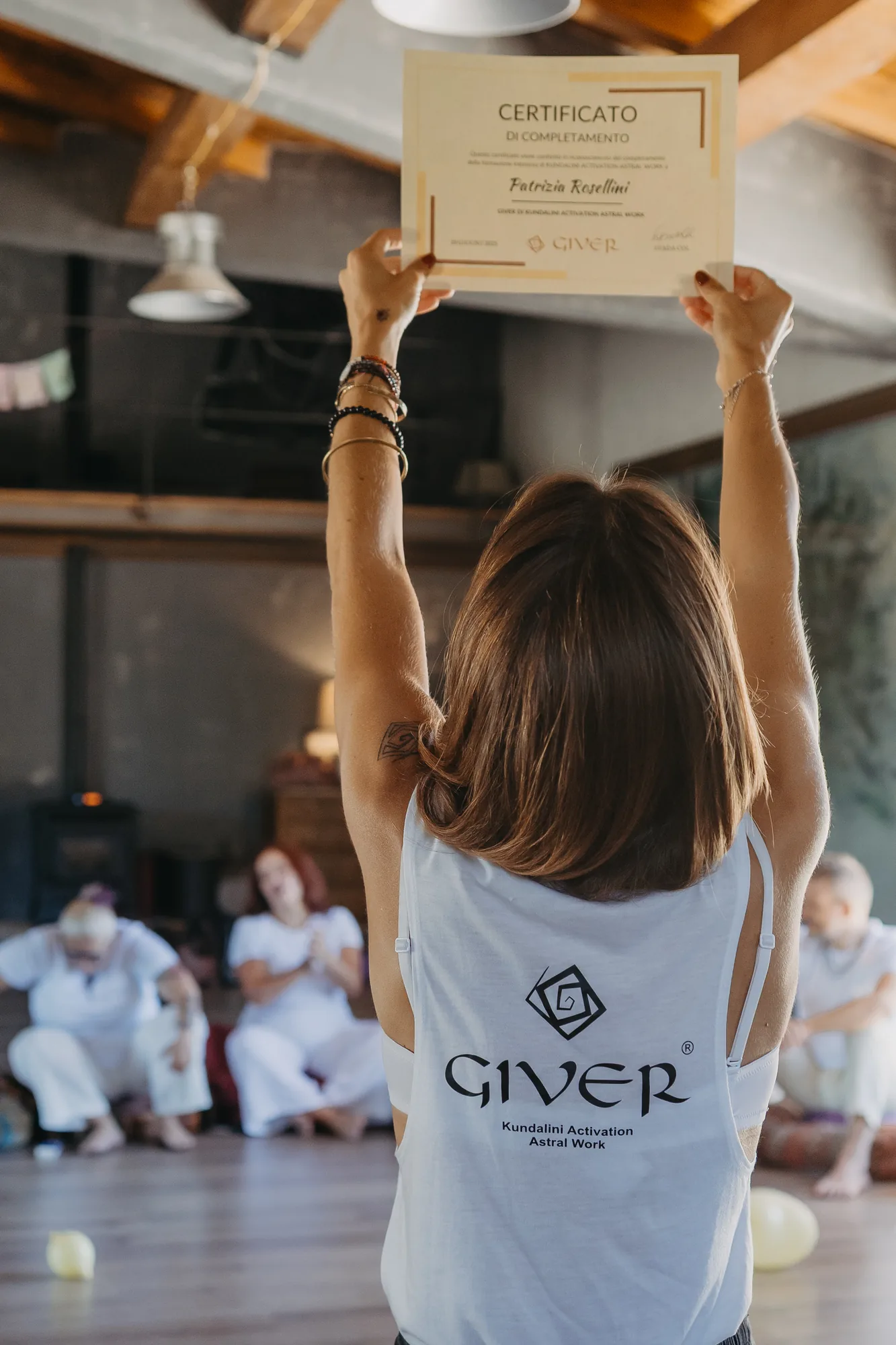 Newly certified facilitator holding up her GIVER® Kundalini Activation Astral Work certification diploma