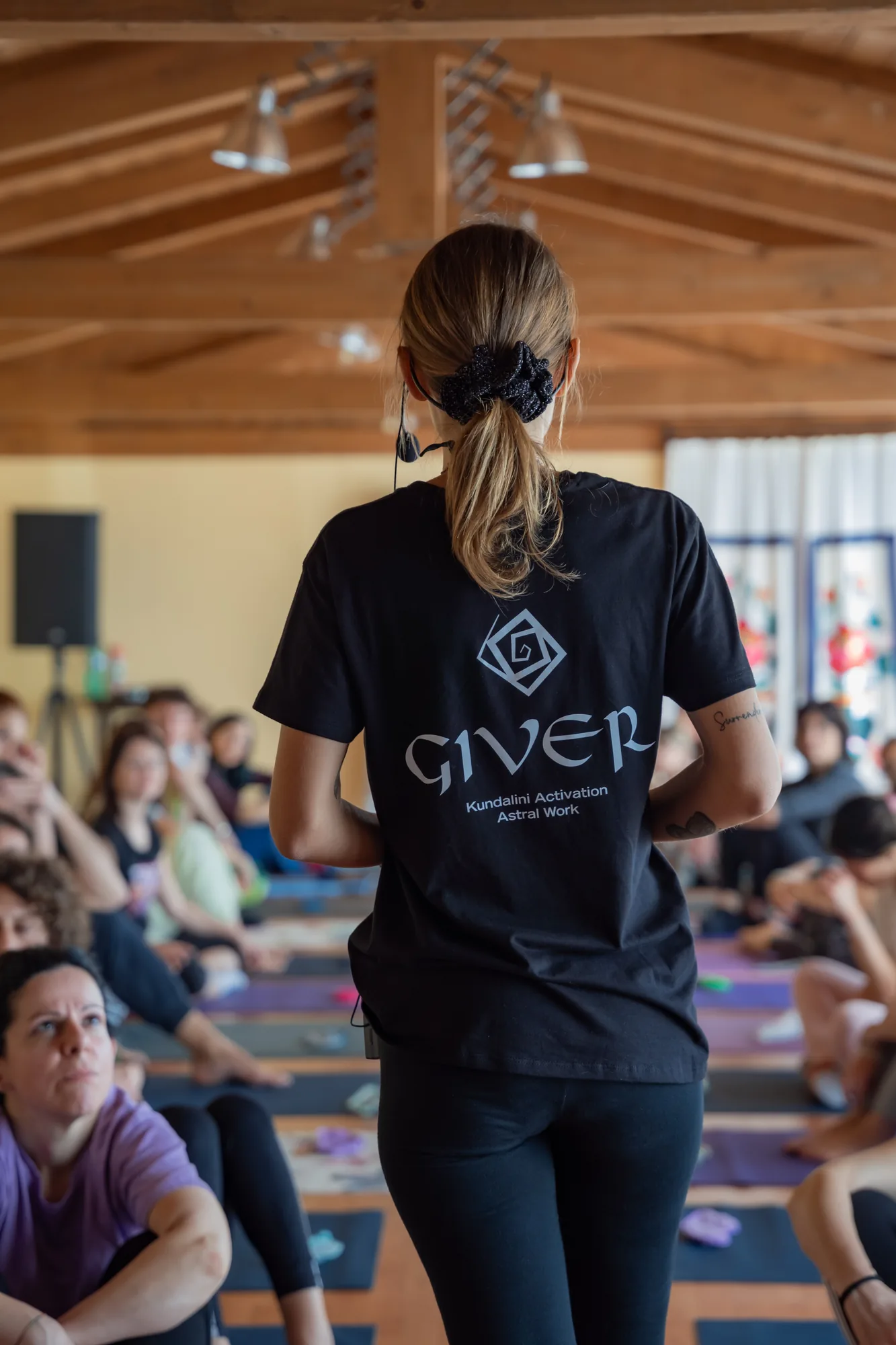 A GIVER® facilitator standing before a seated group, speaking before a Kundalini Activation Astral Work session begins