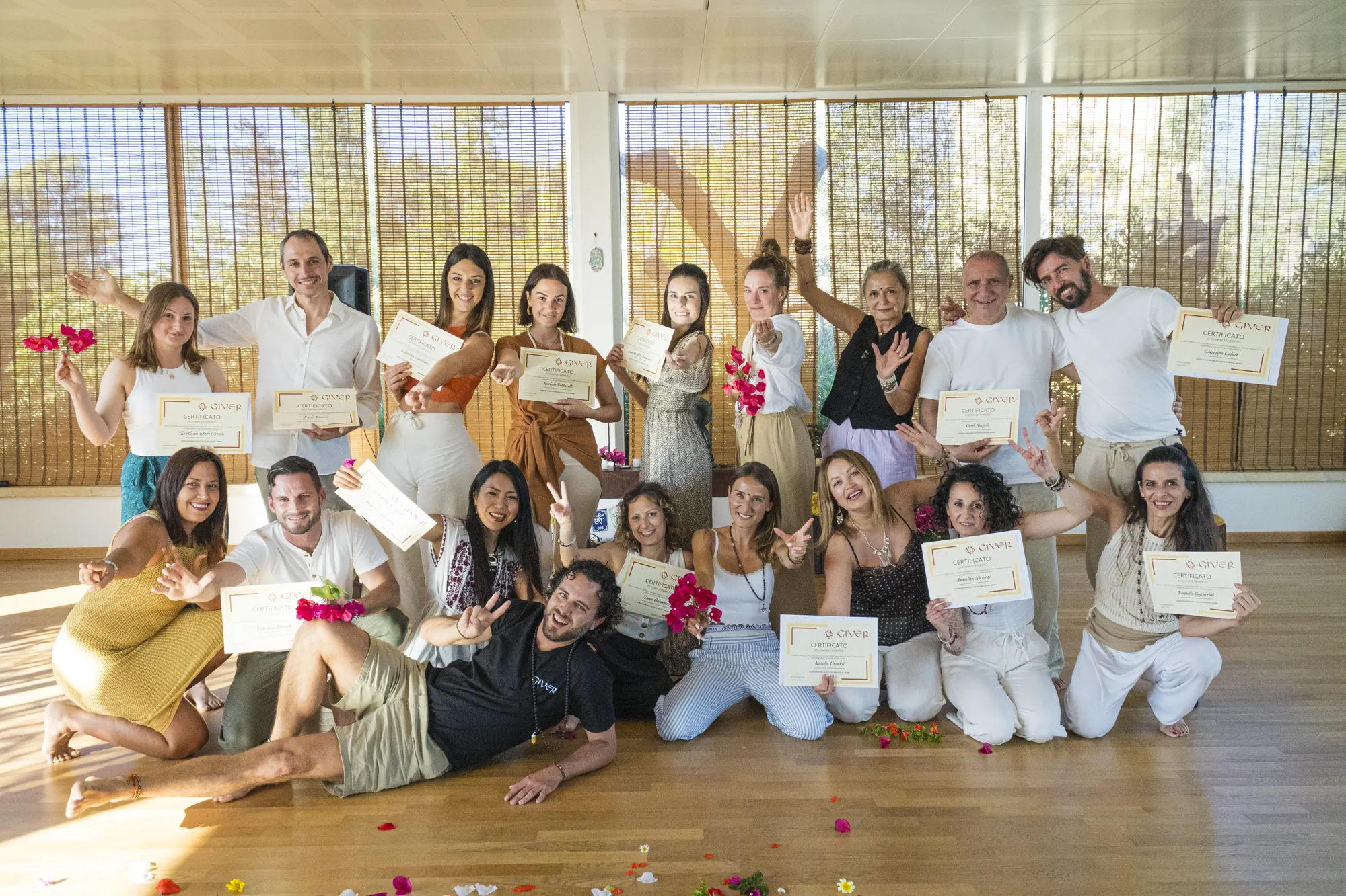2023 GIVER® facilitator training graduates celebrating with certificates in a sunlit Italian retreat hall