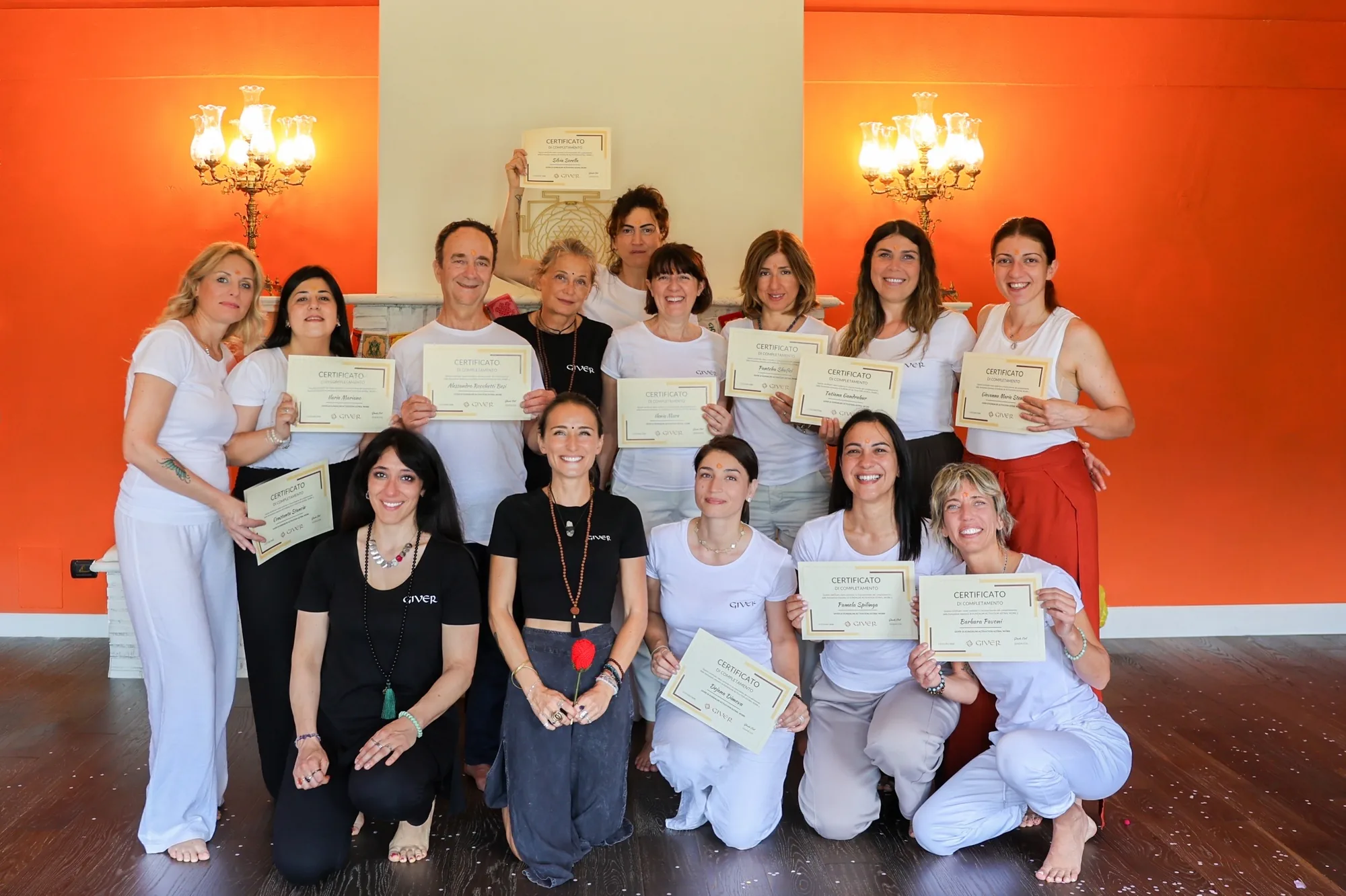 Second 2026 GIVER® Kundalini Activation facilitator training group holding certificates in a warm-toned Italian villa room