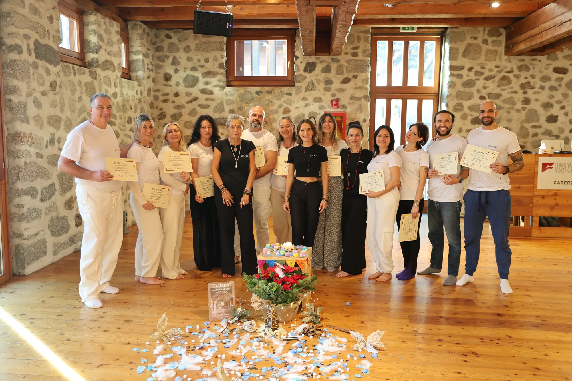 2026 GIVER® facilitator training graduates with certificates in a stone-walled hall in Italy