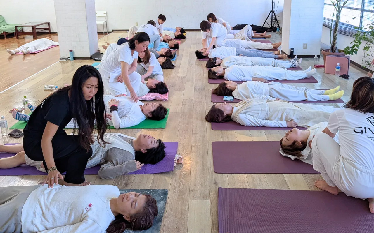 GIVER® facilitators moving between participants lying on mats during a Kundalini Activation Astral Work session in Japan