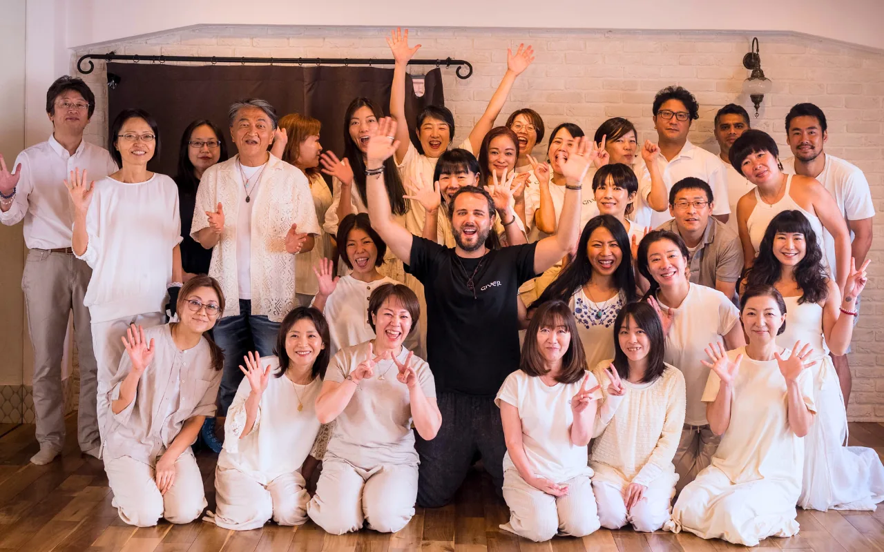 Large group of participants and GIVER® facilitators celebrating after a Kundalini Activation Astral Work session in Tokyo