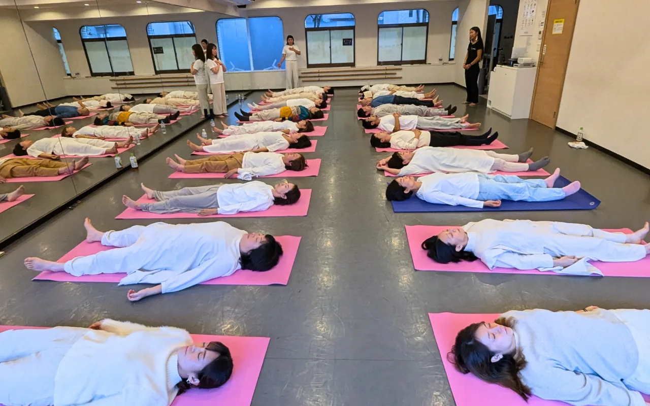 Large hall of participants lying on mats during a GIVER® Kundalini Activation Astral Work session in Japan