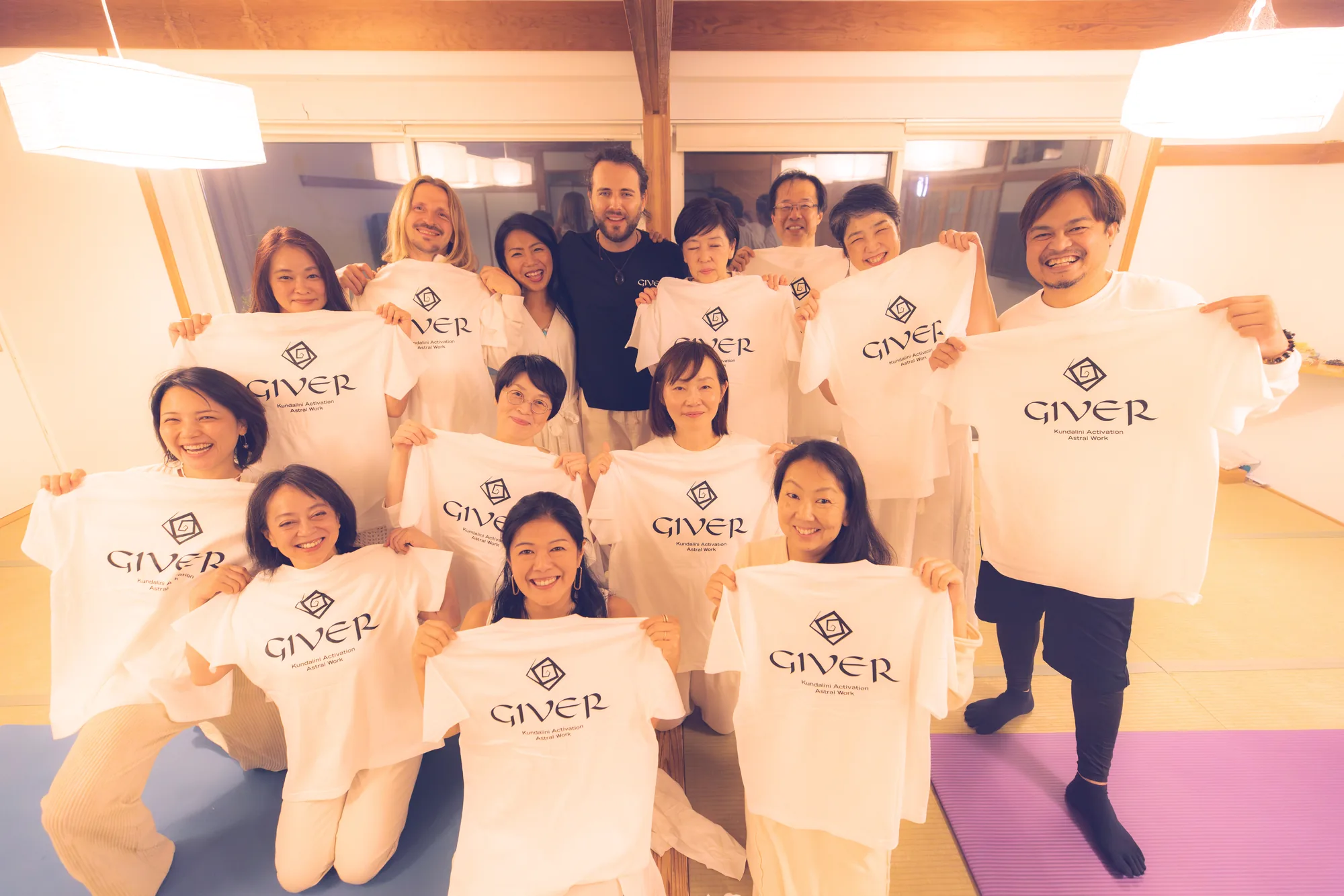 Graduates of the GIVER® Kundalini Activation Astral Work facilitator training in Japan holding their GIVER® shirts